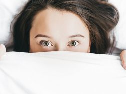 woman-peeking-out-from-under-bed-covers.jpg