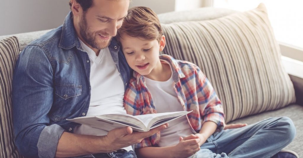 photo of a dad reading with his son on the couch