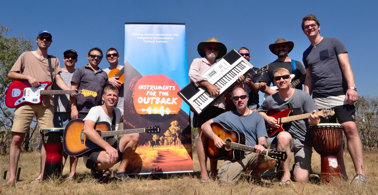 christian musicians posing with instruments in front of a banner for instruments for the outback